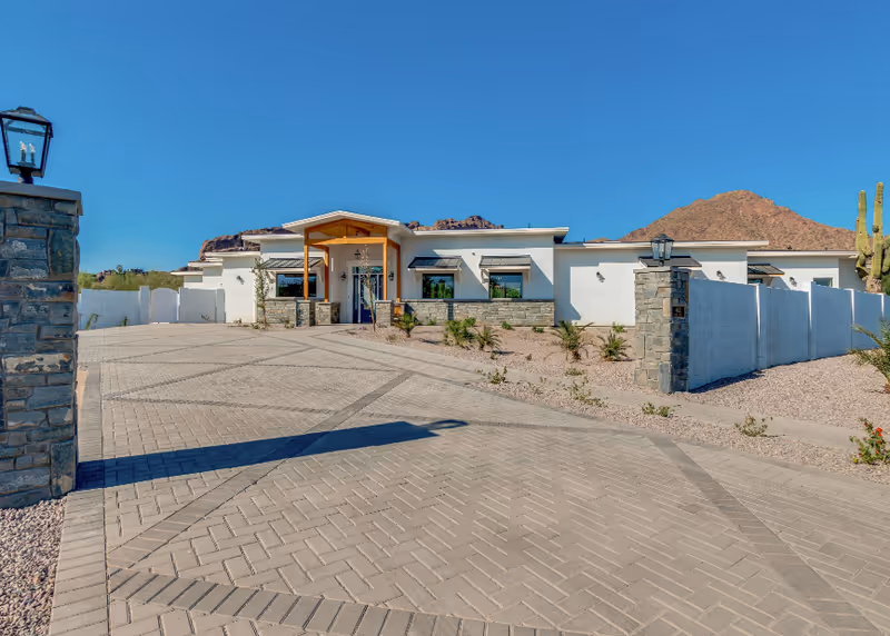 A modern single-story senior living facility with a wide, paved entrance and desert landscaping.