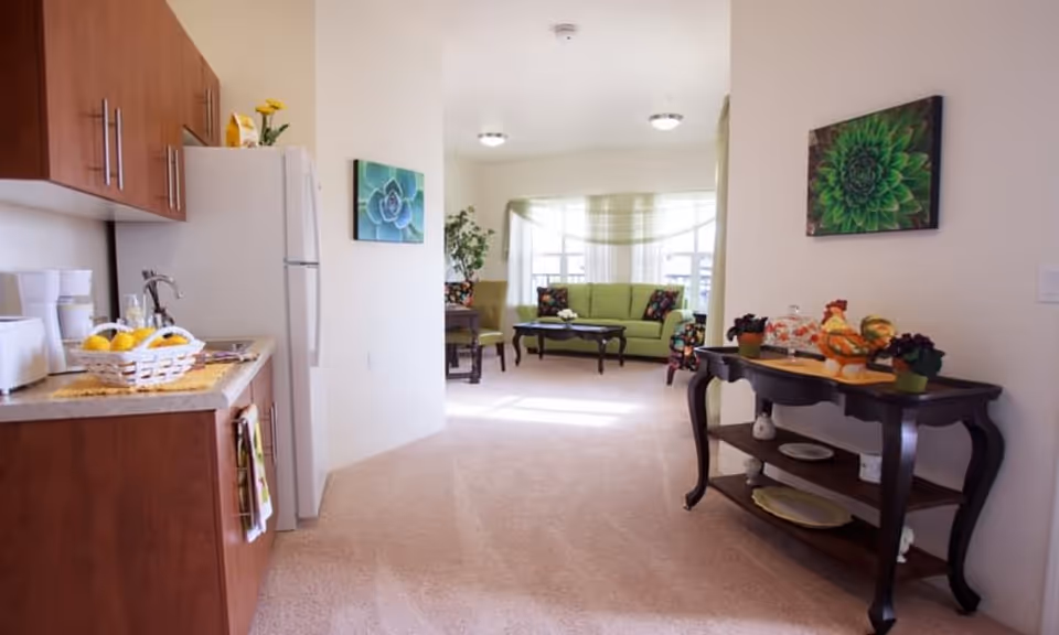 Open studio-style apartment with a kitchenette on the left and a bright living room with a green sofa in the background.