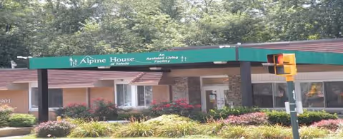 Exterior view of Alpine House of Toledo assisted living facility entrance with green sign.
