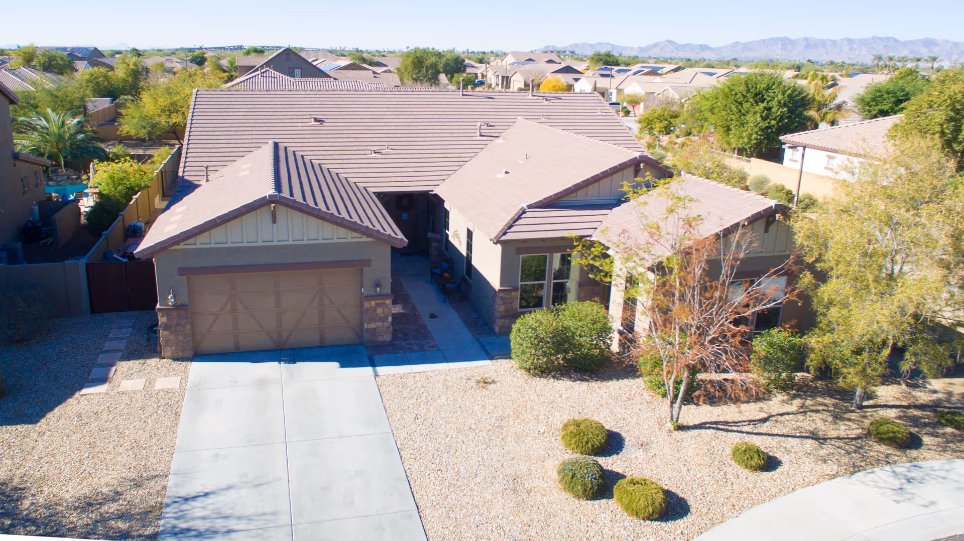Aerial view of a residential building with a driveway and landscaped front yard.