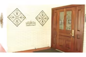 Entrance area of College Street Health Care Center featuring a wooden door with glass panels and decorative metal wall art on a white brick wall.