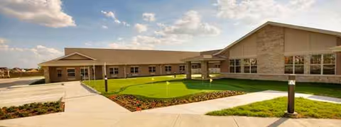 Front exterior view of a single-story senior living facility with manicured lawn.