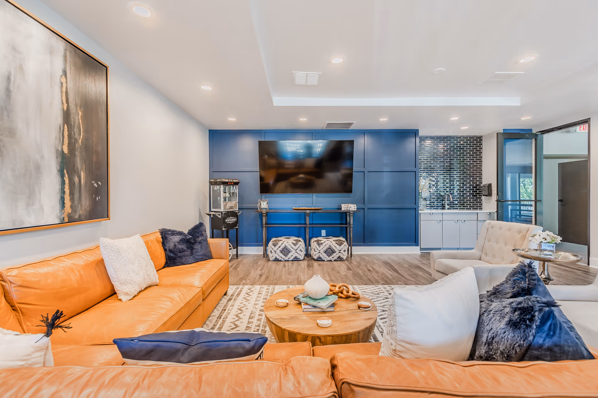 Modern lounge area with orange and white sofas, coffee table, and a blue wall.