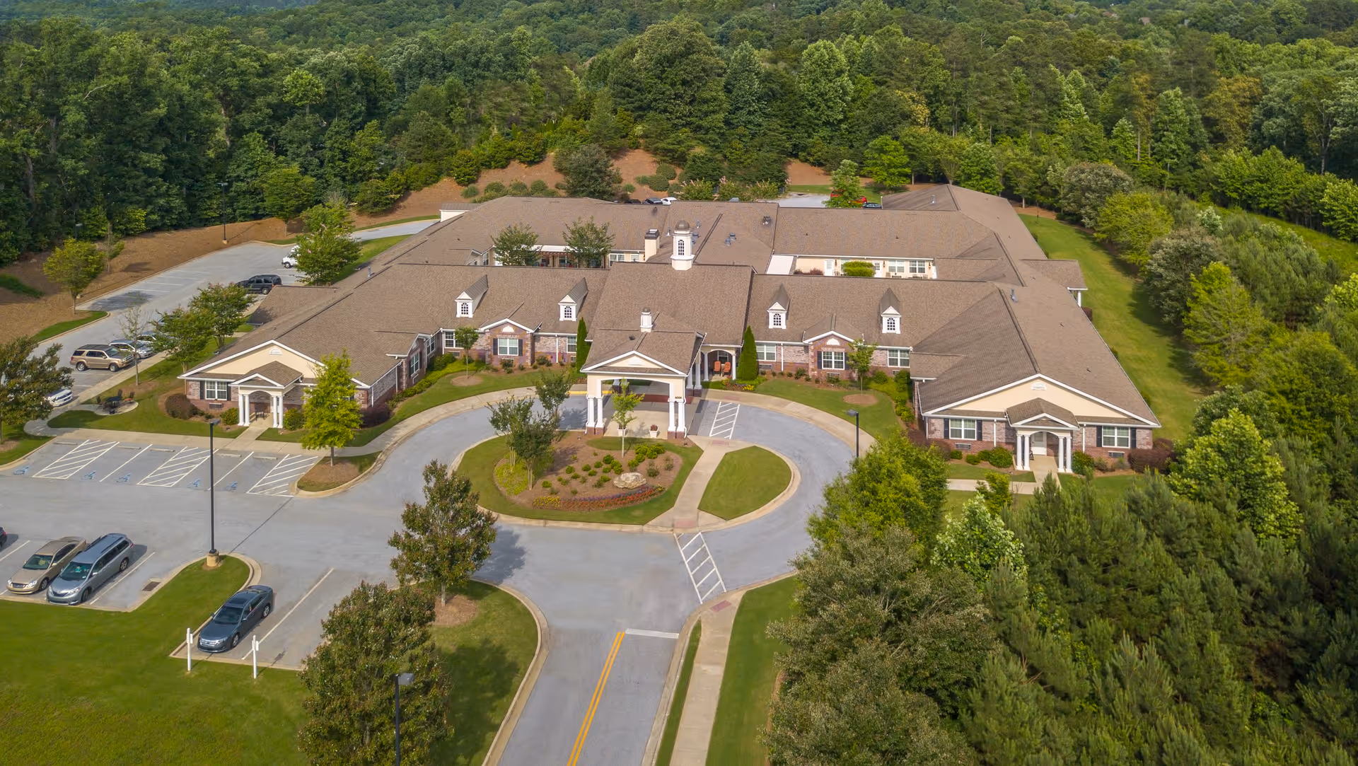 Aerial view of Benton House of Sugar Hill, a large single-story building surrounded by trees and greenery, with a circular driveway and parking lot in front.