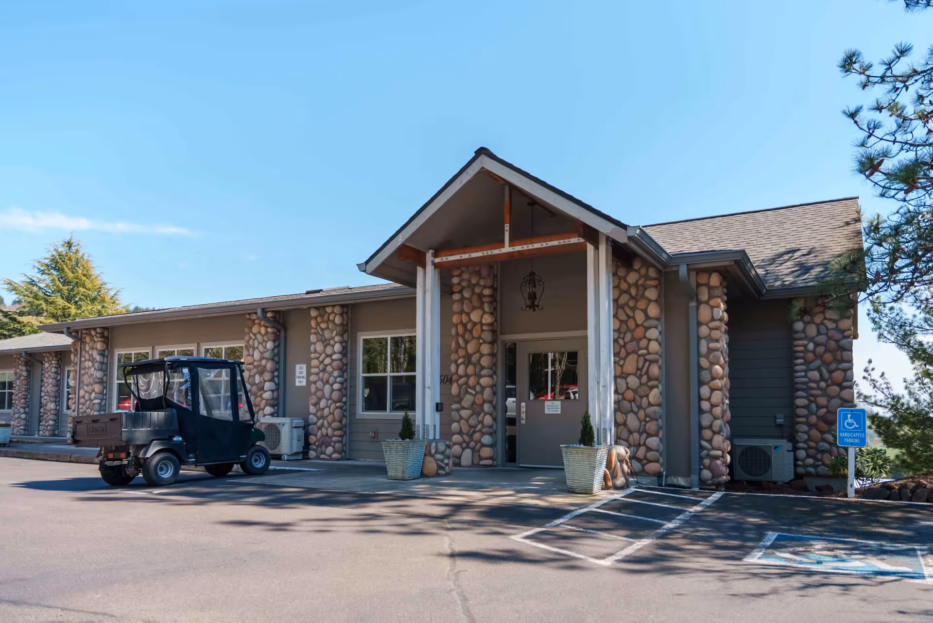 Front exterior view of a retirement community building with stone columns and a parking area.