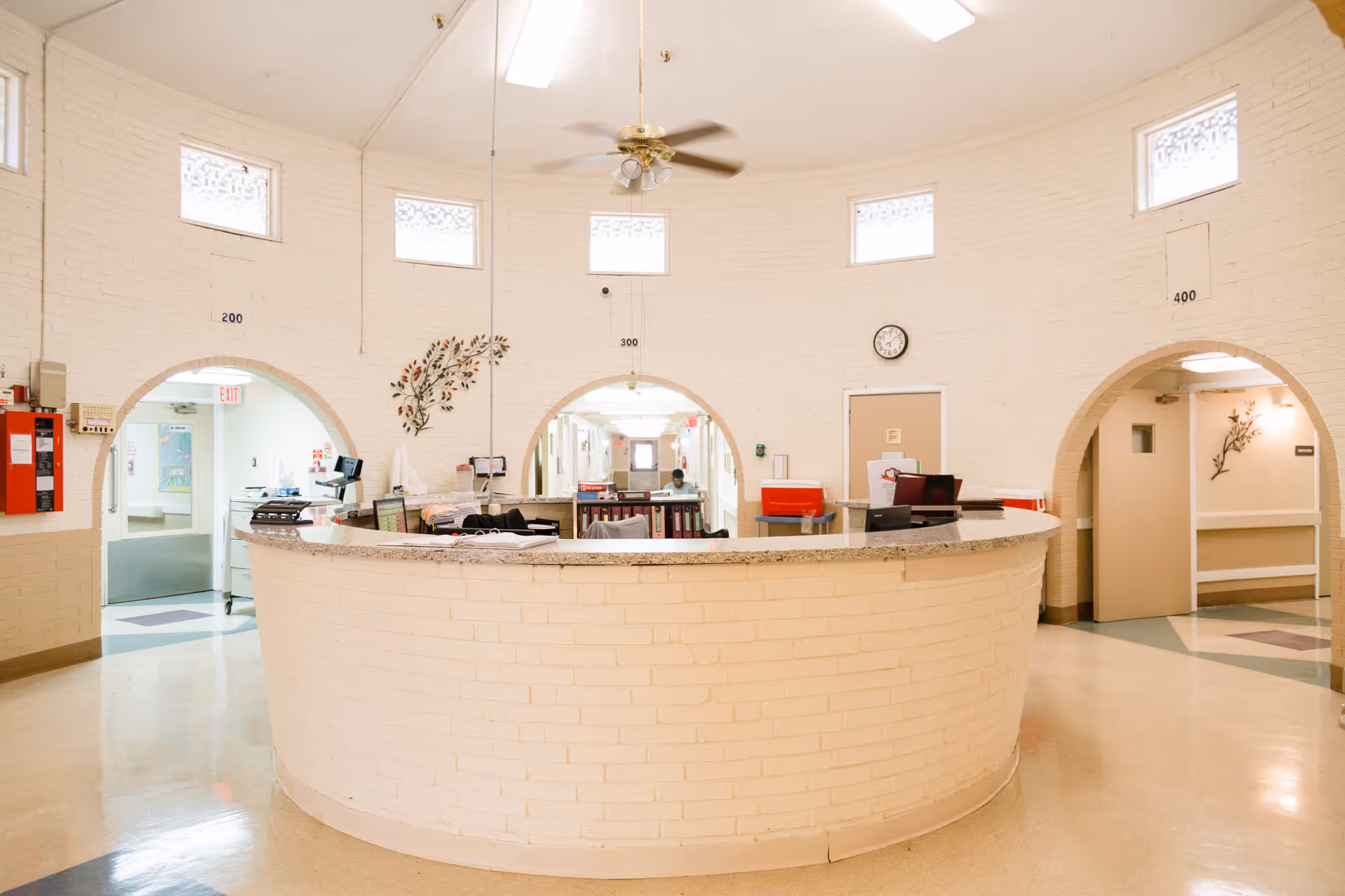 Circular reception/nurse station inside a bright, round interior space with arched doorways and a ceiling fan.