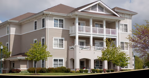 Exterior view of Carroll Lutheran Village building with balconies, beige siding, and trimmed landscaping.