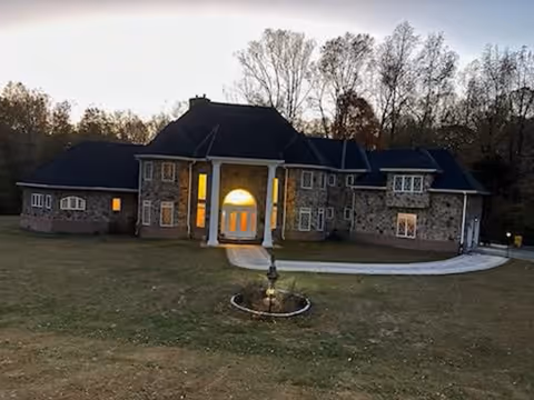 Stone-built senior living facility with lit front doorway and curved driveway.