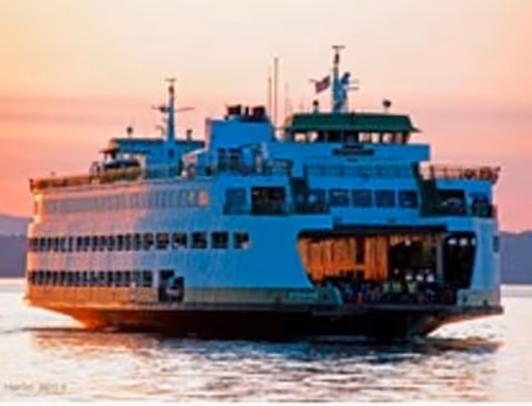 A large ferry boat sailing on calm water at sunset.