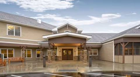 Front exterior of a senior living facility with a covered entrance and glass doors.