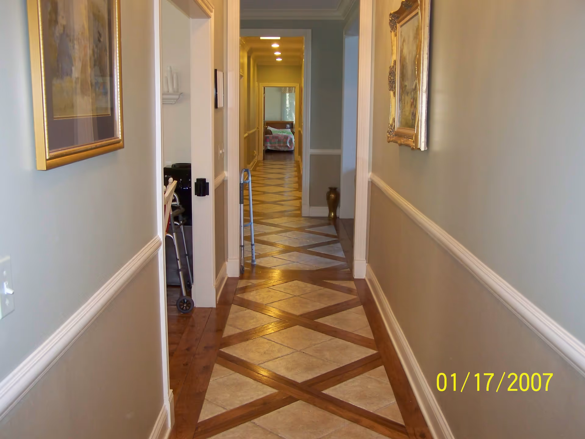 Interior hallway in a senior living facility with tiled floor and wall art.