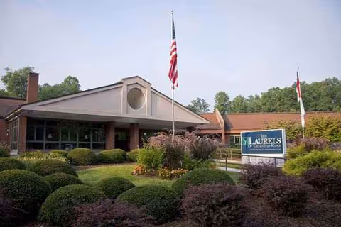 Exterior view of The Laurels of GreenTree Ridge with landscaped entrance and flags.
