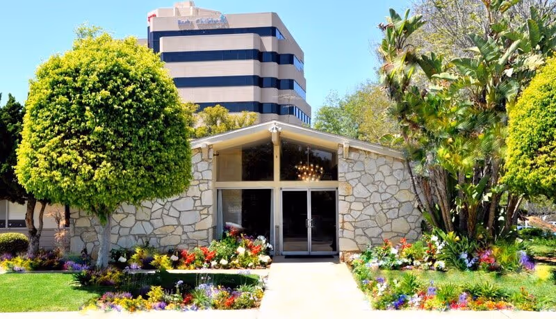 Abby Gardens facility entrance with a stone facade and landscaped garden.