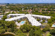 Aerial view of a multi-building senior living complex with a central swimming pool, surrounding trees, and nearby parking.