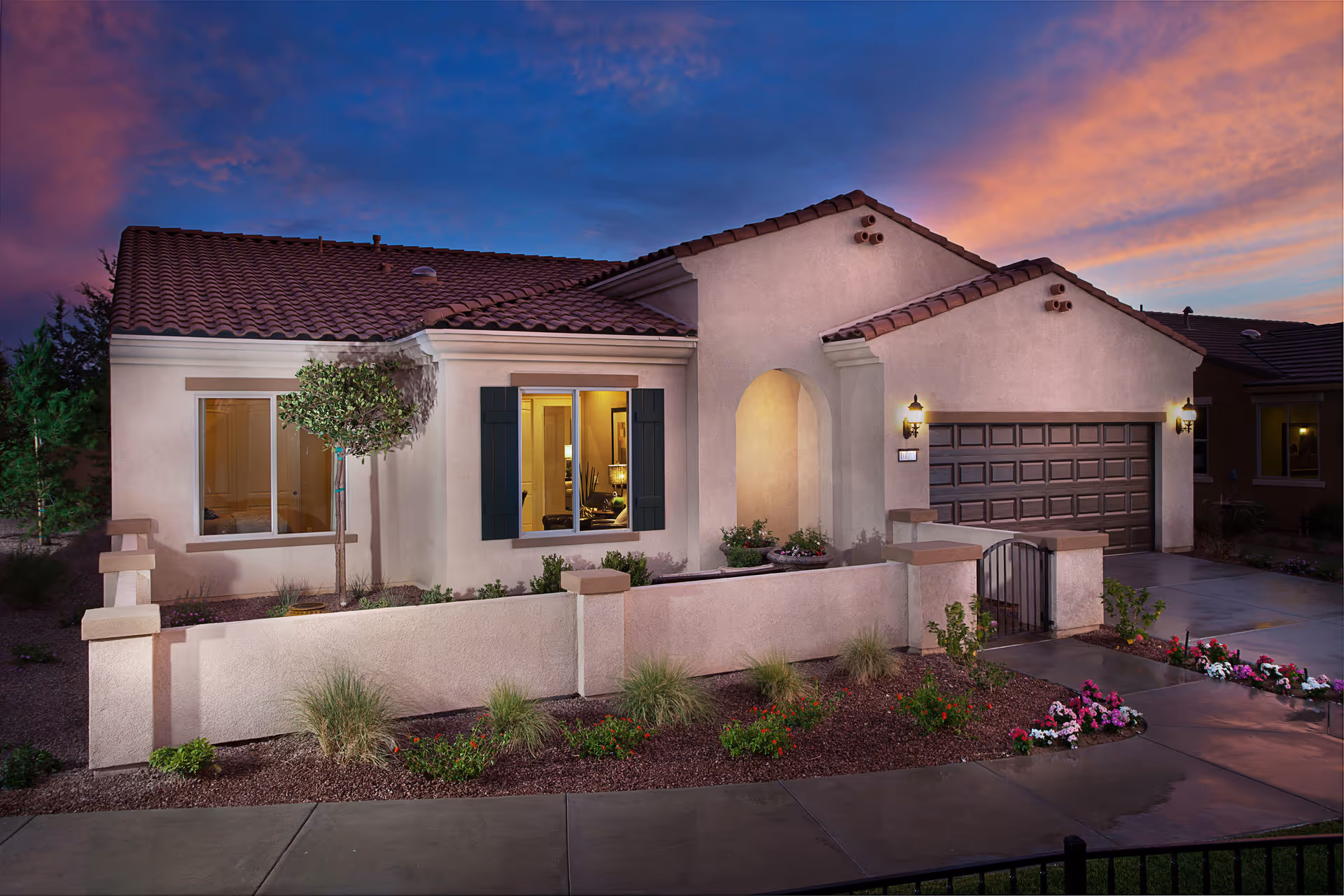 Front exterior of a single-story stucco house with a tiled roof, small walled courtyard, garage, and evening sky.