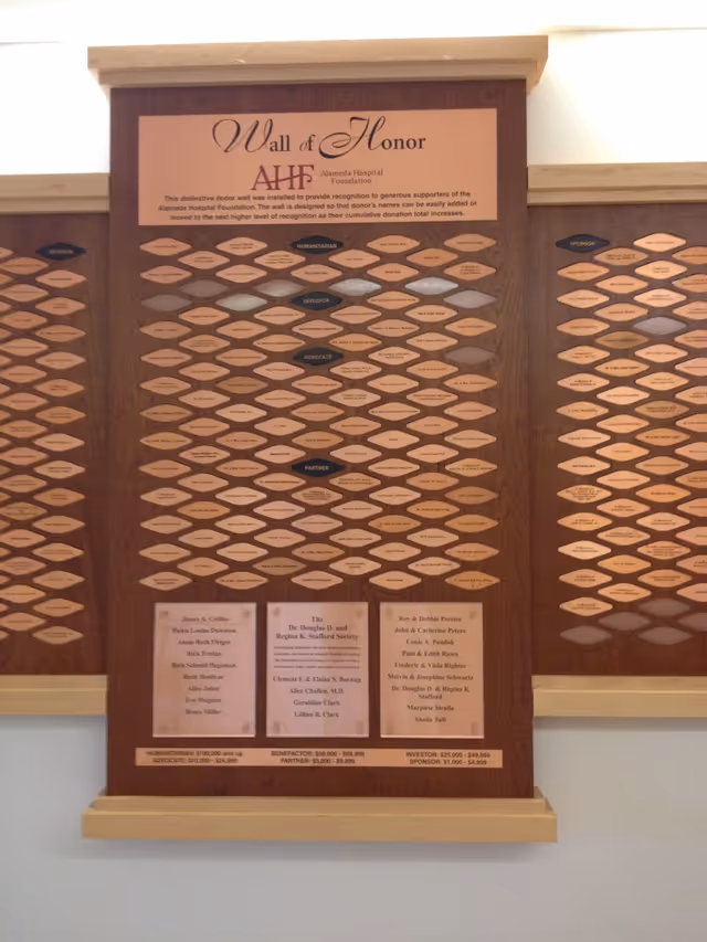 A wooden 'Wall of Honor' donor plaque at Alameda Hospital with many small engraved name plates.