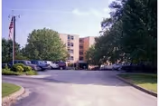 Heritage Towers residential building with a parking lot and large trees in front.