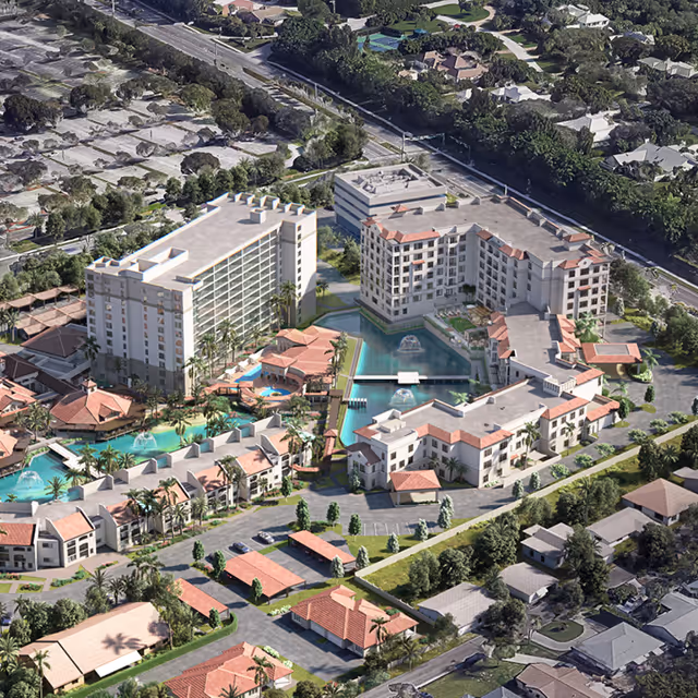 Aerial view of The Waterford senior living facility showing multiple buildings with red-tiled roofs surrounding a central water feature with fountains, landscaped grounds, swimming pools, parking areas, and nearby residential neighborhood.