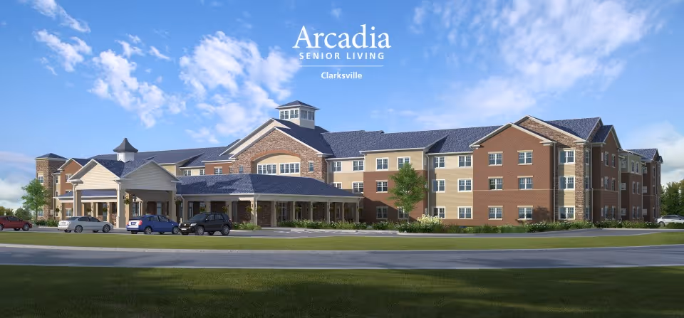 Large three-story senior living building with brick and siding facade, a covered entrance, parked cars, and a blue sky above.