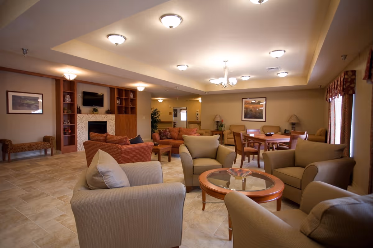 Spacious communal living room with armchairs, sofas, a fireplace, and a dining table.