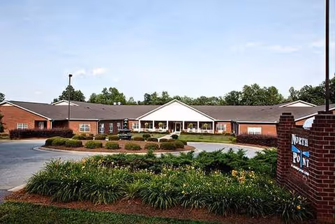 Exterior view of a single-story brick senior living facility with circular driveway and landscaped entrance.