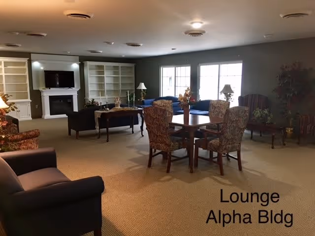 Spacious lounge with multiple seating areas, a table and chairs, built-in bookshelves, a fireplace, and large windows.