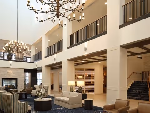 Spacious two-story lobby with multiple seating areas, large chandeliers, a fireplace, and an upper balcony railing.