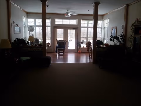 A common living room area with sofas, chairs, columns and large windows/doors letting in daylight.