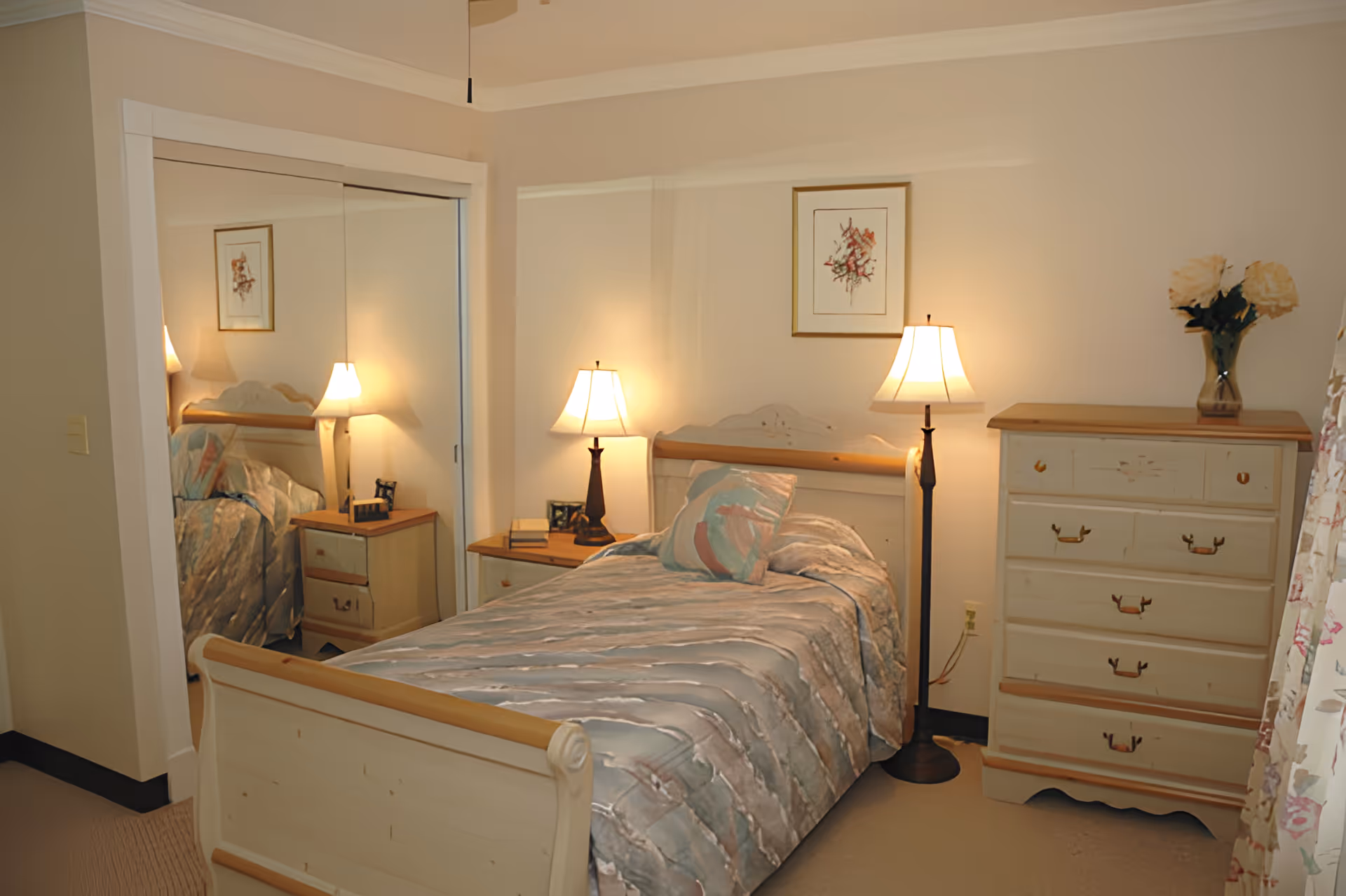 Cozy bedroom with a single bed, bedside tables and lamps, a dresser, and mirrored closet doors.