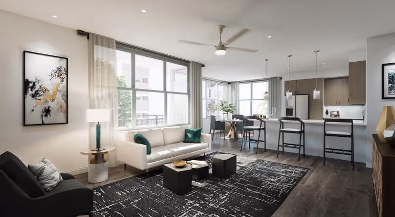 Bright open-plan living room and kitchen with a white sofa, black rug, kitchen island with barstools, and large windows.