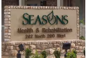 Stone sign for Seasons Health & Rehabilitation located at 242 North 200 West, surrounded by small plants and landscaping.