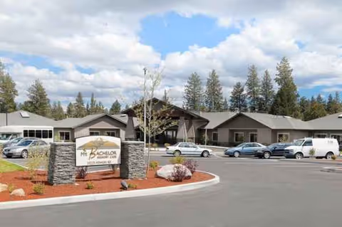 Exterior view of Mt. Bachelor Memory Care with front entrance, sign, and parked cars.