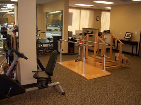 Rehabilitation gym with parallel bars and exercise equipment inside a clinic.