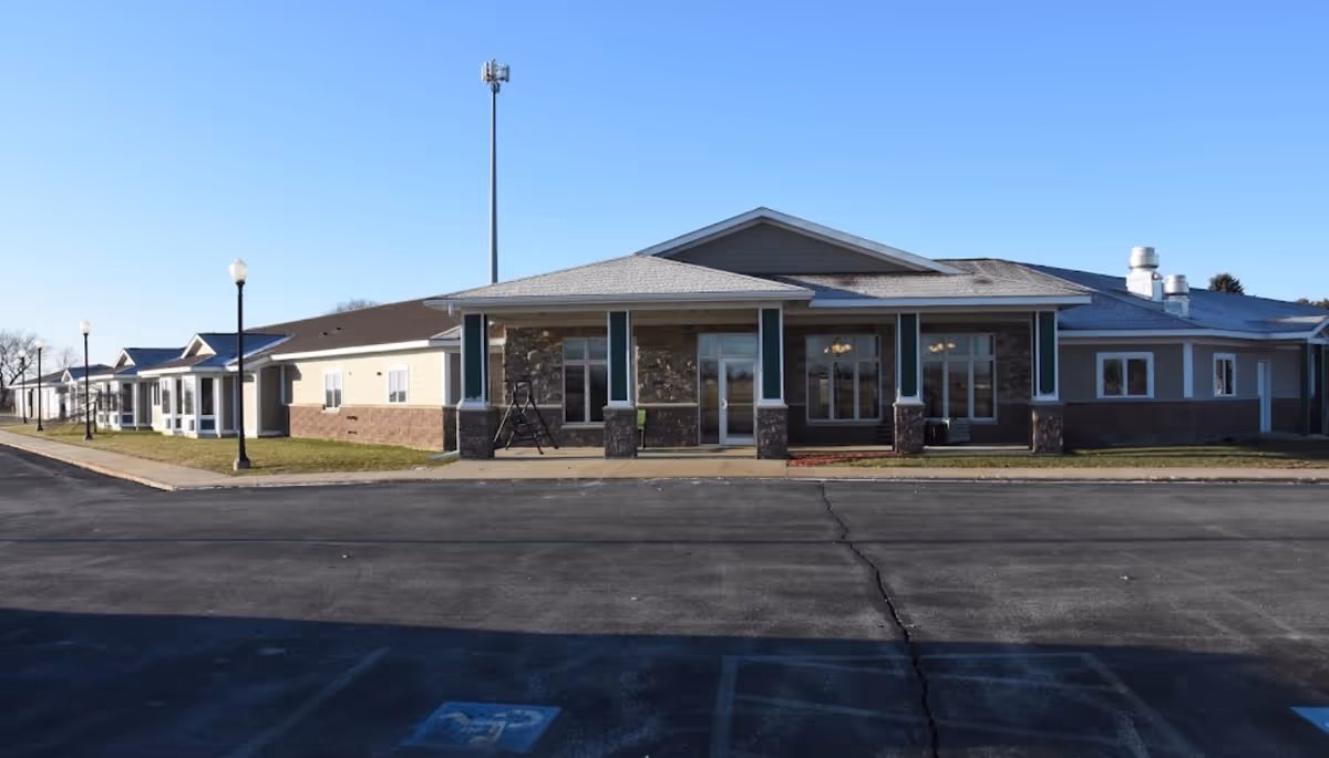 Single story assisted living facility exterior with brick and stone facade and a paved front road.