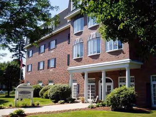 Brick senior living facility exterior with a covered entrance and surrounding greenery.