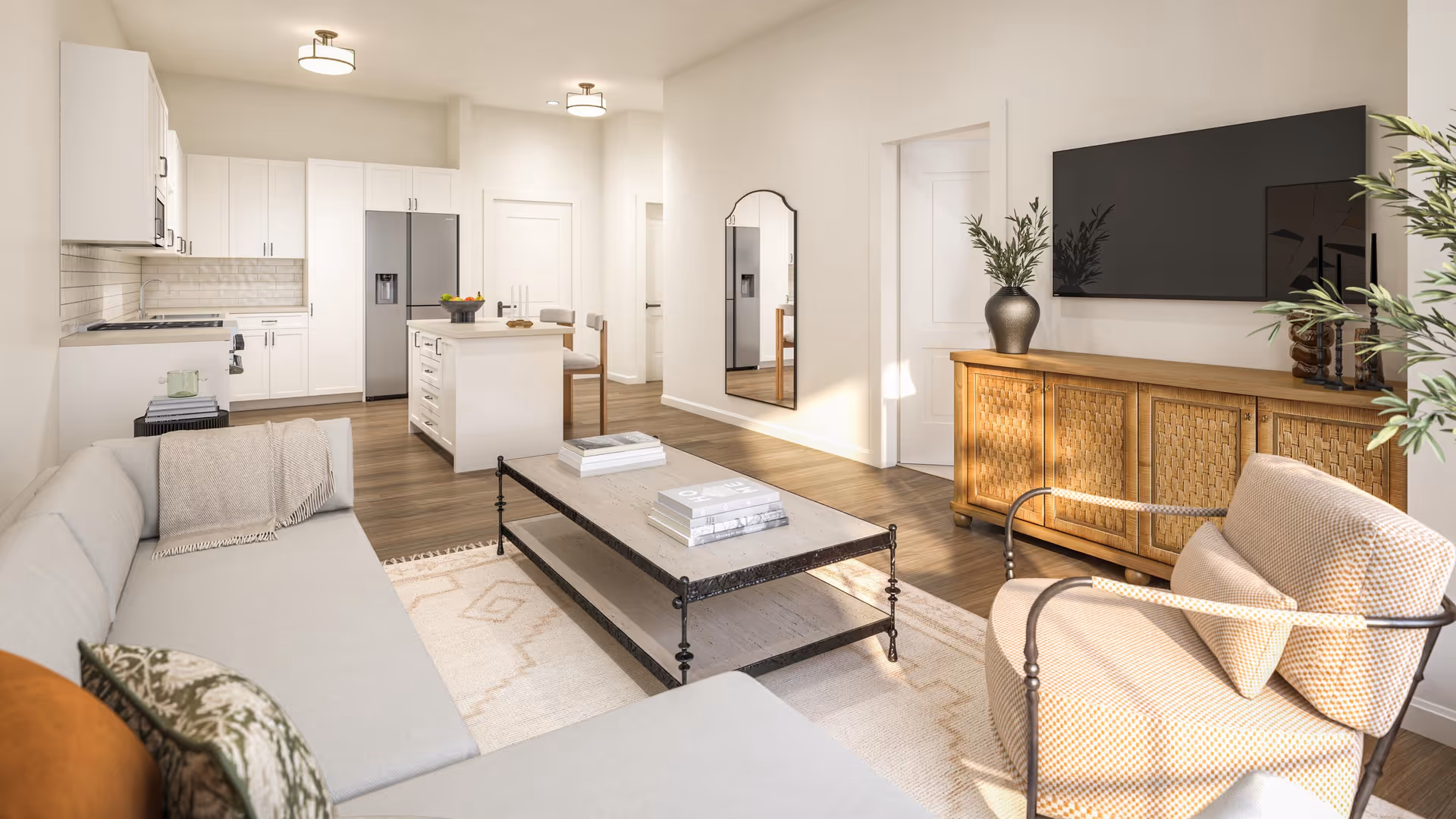 Bright open-plan living room and kitchen with a sofa, coffee table, armchair, wall-mounted TV, and a central kitchen island.