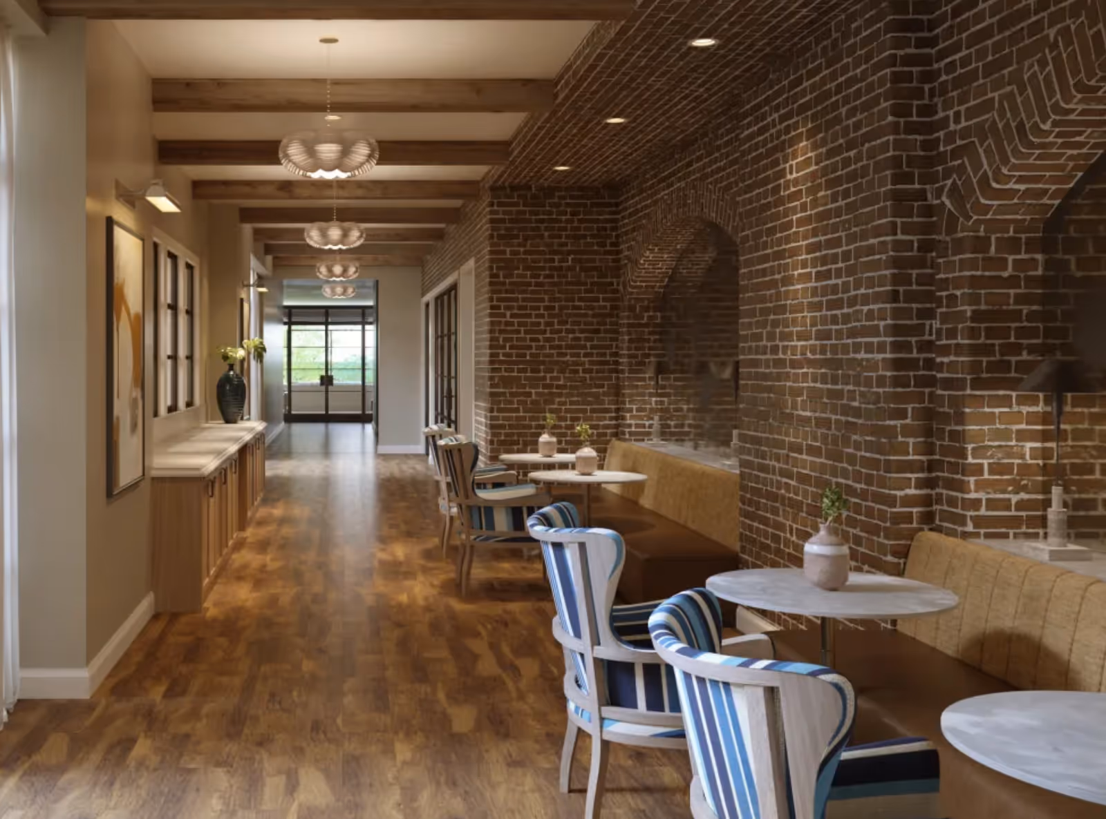 A long interior corridor with wooden beams and floors, an exposed brick arched wall, and small round tables with striped upholstered chairs.