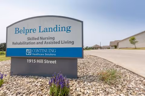 Entrance sign reading 'Belpre Landing Skilled Nursing Rehabilitation and Assisted Living' with the address '1915 Hill Street' in a landscaped area outside the facility.