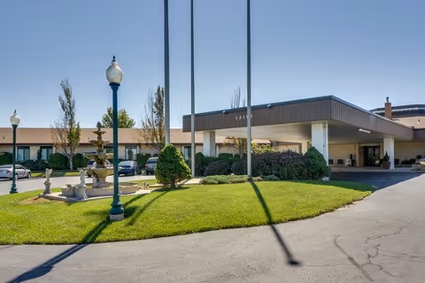 SummitView Terrace exterior with a curved driveway, manicured lawn, streetlamps, and a covered entrance.