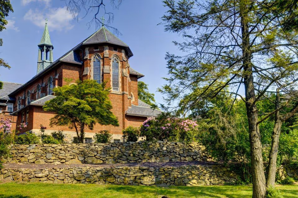 Exterior view of Saint Francis Residential Community with brick building, stone wall, and trees.