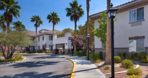 Exterior view of Heritage Springs Assisted Living and Memory Care with palm trees and curved driveway