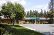 Rockwood at Whitworth entrance with green canopies and a brick building amid trees