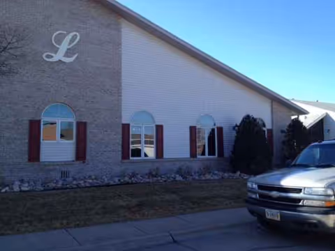Exterior view of Lebensraum Assisted Living building with arched windows and a parked truck.
