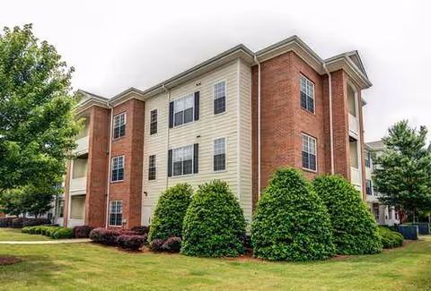 Exterior view of a multi-story senior living building with brick and beige siding.