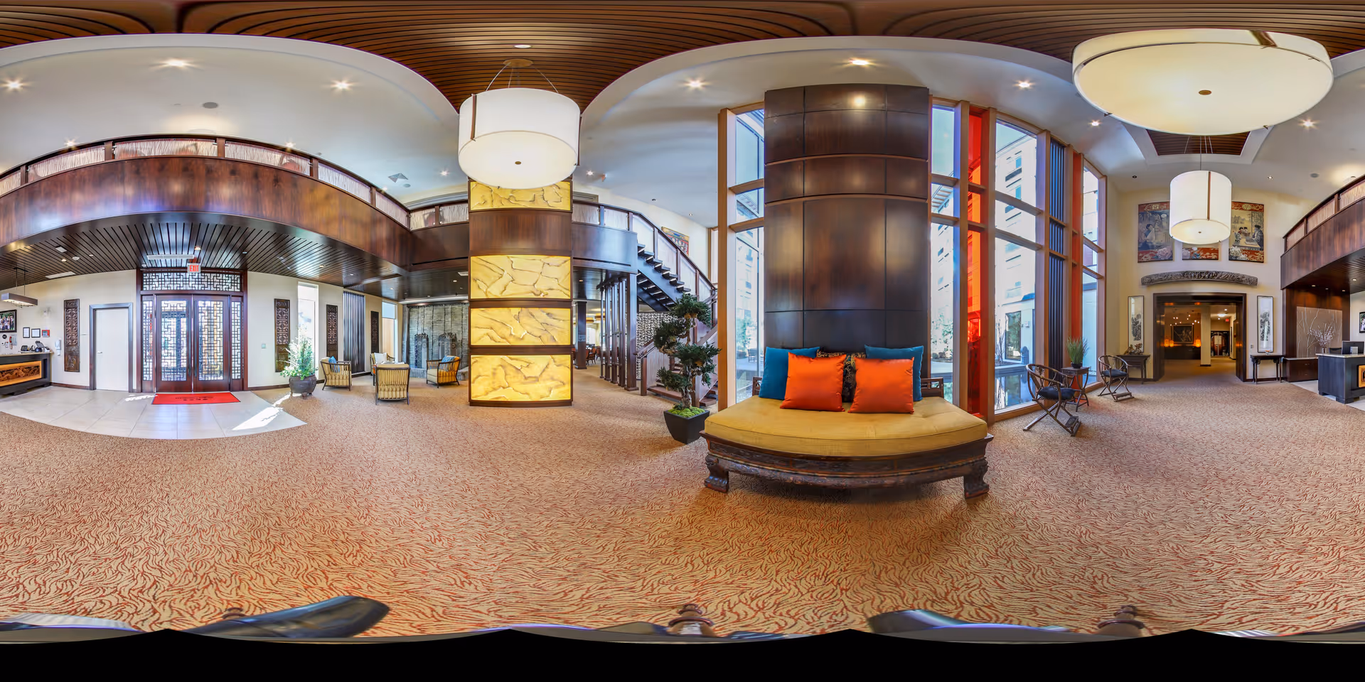 Spacious, well-lit senior living facility lobby with seating areas, large windows, and decorative wood accents.
