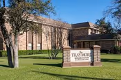 Brick senior living facility entrance with a manicured lawn and a Traymore at Park Cities sign.