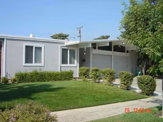 Exterior view of Sunflower Care Home with a grassy lawn, shrubs, and a walkway.