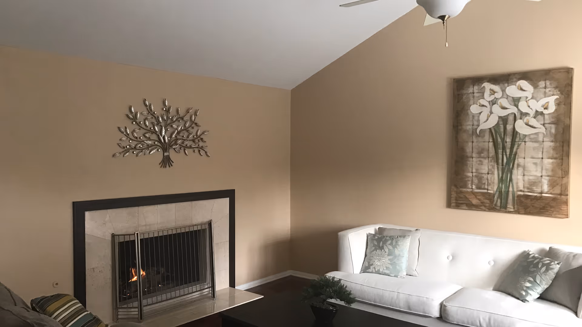 Living room with a white sofa, coffee table, and a fireplace beneath decorative wall art.