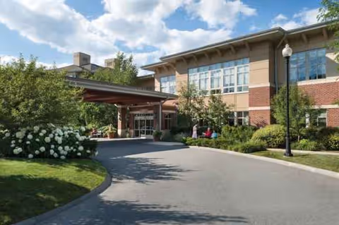 Exterior view of Linden Ponds entrance with driveway, landscaping, and a covered drop-off.
