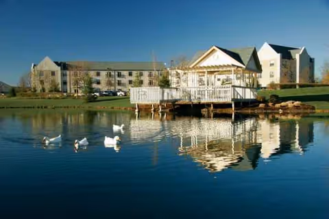 Exterior view of Dublin Retirement Village with a wooden dock over a pond and ducks.